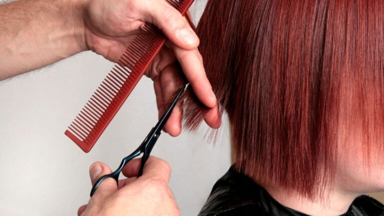 A professional stylist with scissors expertly trimming a woman's hair.