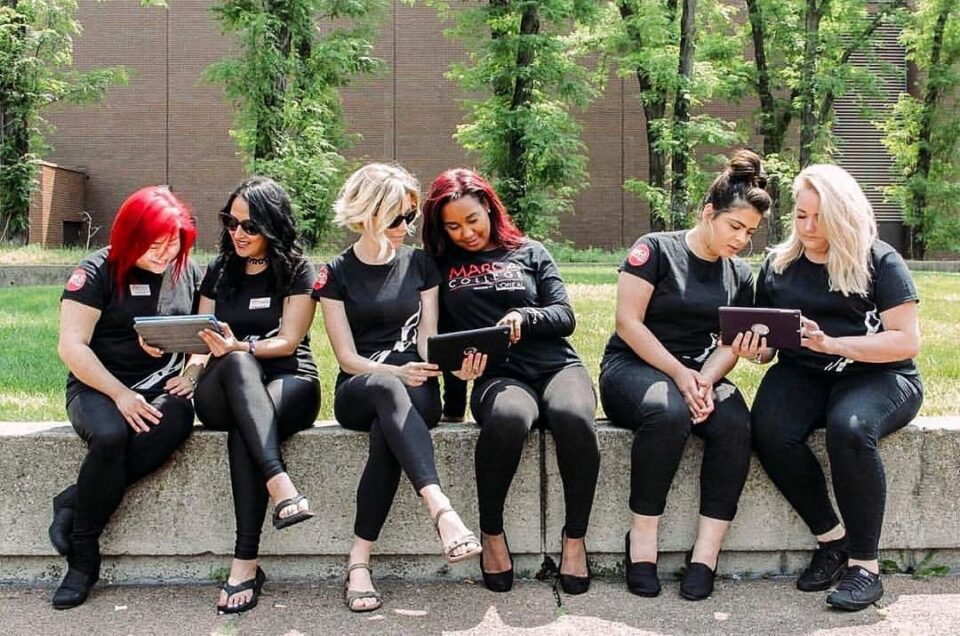 Group of Marca College Hair and Esthetics students sitting on wall having a discussion